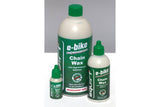 Squirt E-Bike Chain Lube biodegradable wax for drivetrain protection; workshop setting with bike chain and lubricant container.