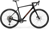 Merida Silex 7000 MY24 gravel bike in black, bronze, and gold with off-road tires and lightweight frame for adventure riding.