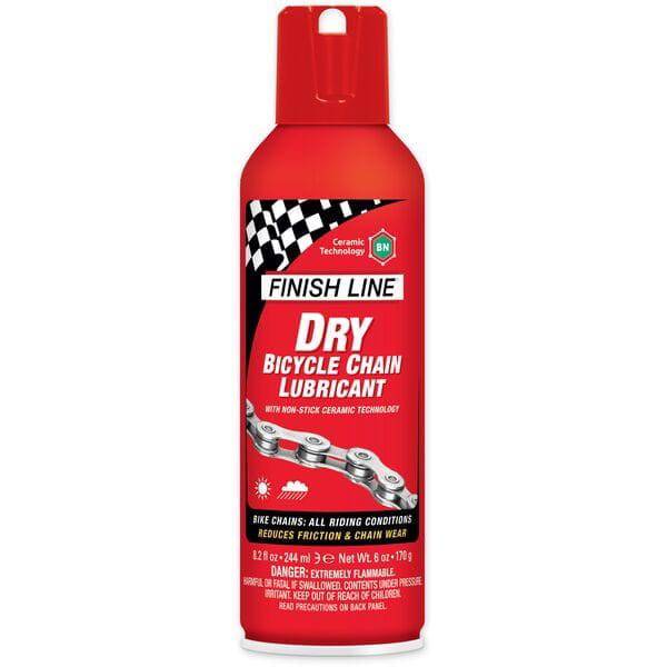 Finish Line Dry Chain Lube Ceramic Tech aerosol bike lubricant in a workshop setting, shown in a box of six 8oz bottles.