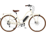 Electra Townie Commute Go! 5i EQ step-thru e-hybrid bike with Bosch motor and integrated racks, parked on a city street.