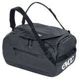 Waterproof EVOC duffle bag with rugged design, 100L capacity, used as a travel pannier and gear bag, showing durable fabric and zippers.