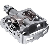 Shimano PD-M324 SPD MTB pedals with one-sided clipless and flat design, showcasing durable cycling component for mountain biking.