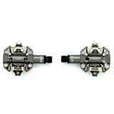 Look X-Track MTB pedals in metallic grey with SPD compatibility and adjustable tension, mounted on a bicycle crank.