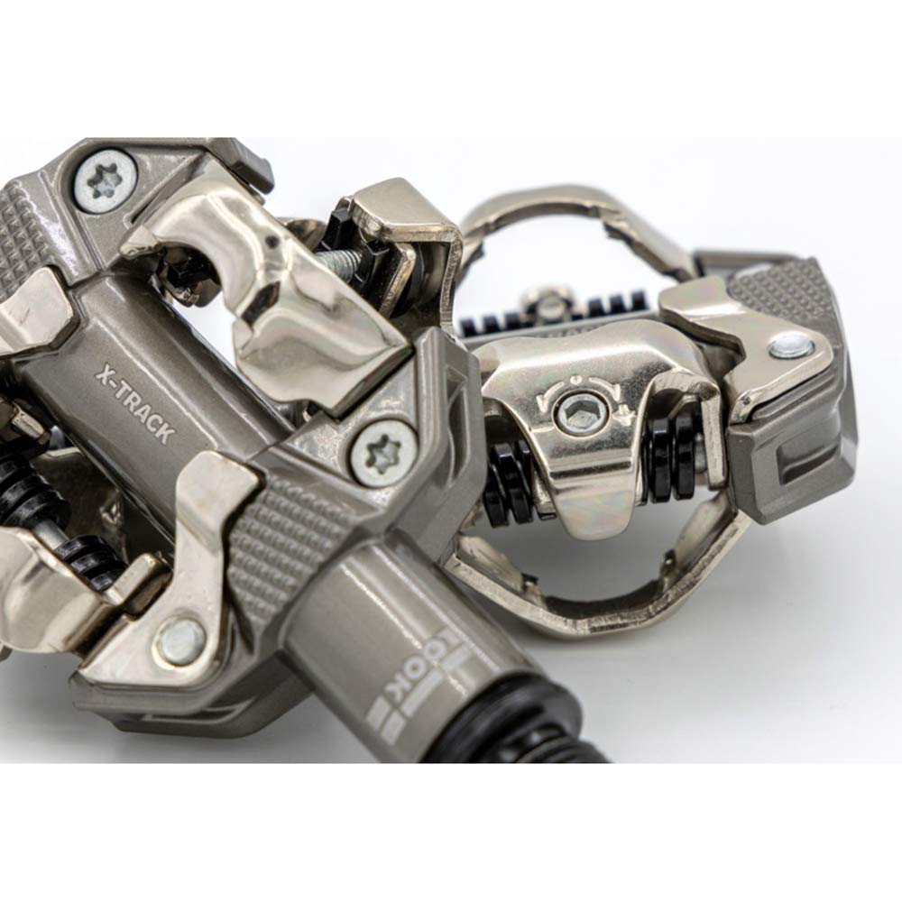 Look X-Track MTB pedals in metallic grey with SPD compatibility and adjustable tension, shown mounted on a bicycle crank.
