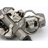 Look X-Track MTB pedals in metallic grey with SPD compatibility and adjustable tension, shown mounted on a bicycle crank.