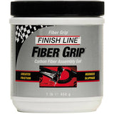 Finish Line Fiber Grip carbon fiber assembly gel tub for bike components, shown in a workshop setting.