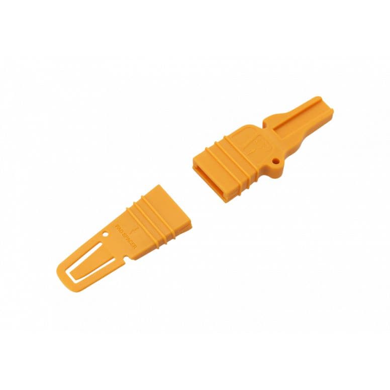 Jagwire yellow disc brake pad spacer and bleed block for hydraulic bike brakes, used in workshop maintenance and bleeding.