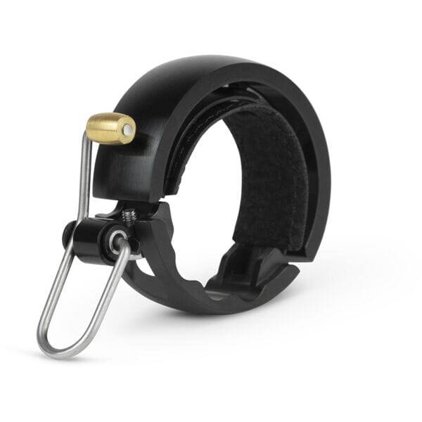 Knog Oi Luxe large bike bell in matte black with clear, resonant sound mounted on a bicycle handlebar.
