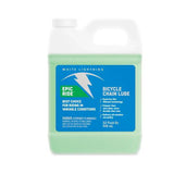 White Lightning Epic Ride synthetic chain lubricant for bikes, shown in a workshop setting with a bottle of long-lasting bike lube.