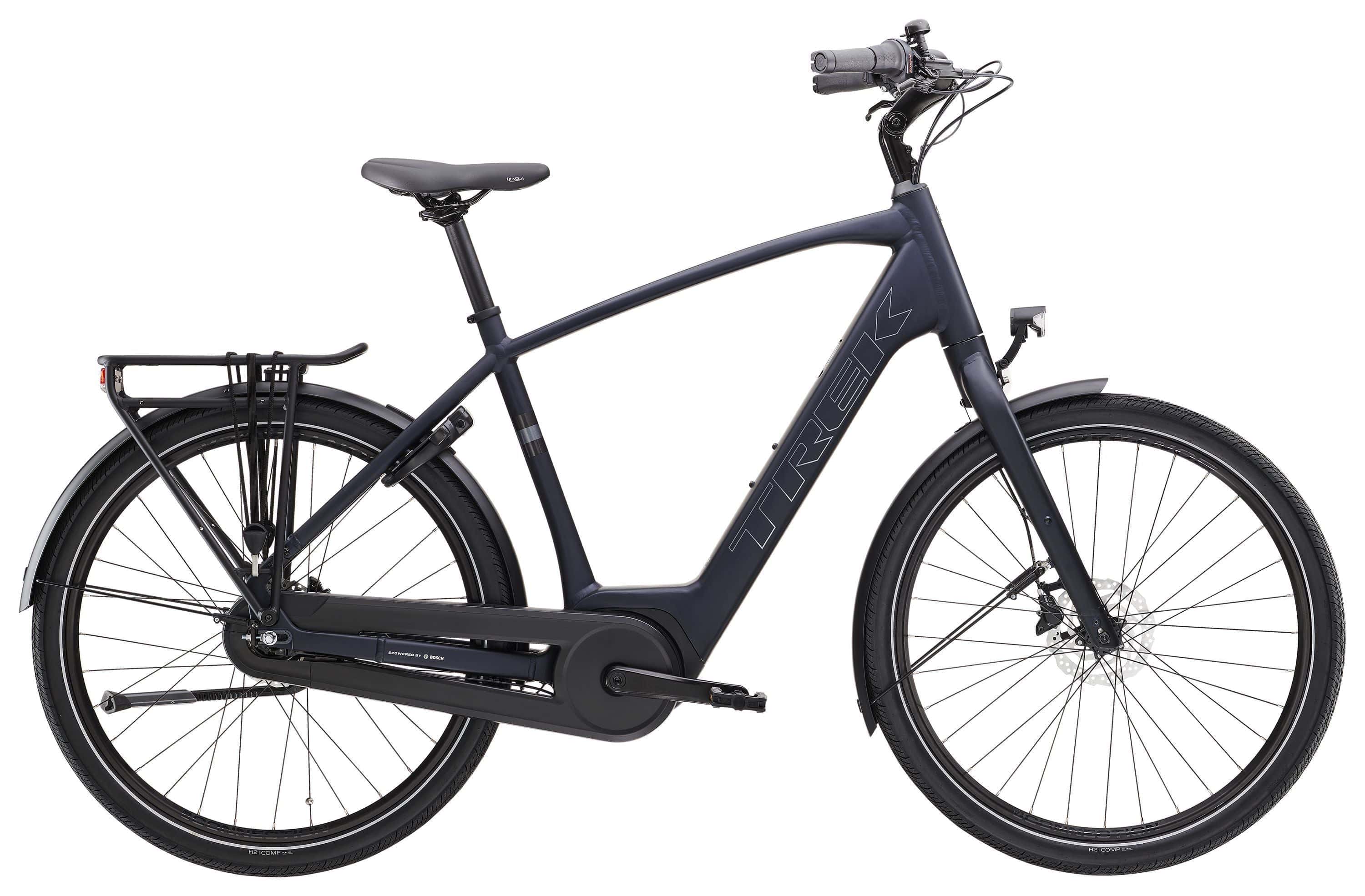 Trek District+ 1 2025 electric hybrid bike for urban commuting, shown in a city street setting with sleek frame and handlebars.