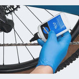 Park Tool CL-1.2 eco-friendly synthetic chain lube bottle, suitable for bike lubrication, with a workshop setting background.
