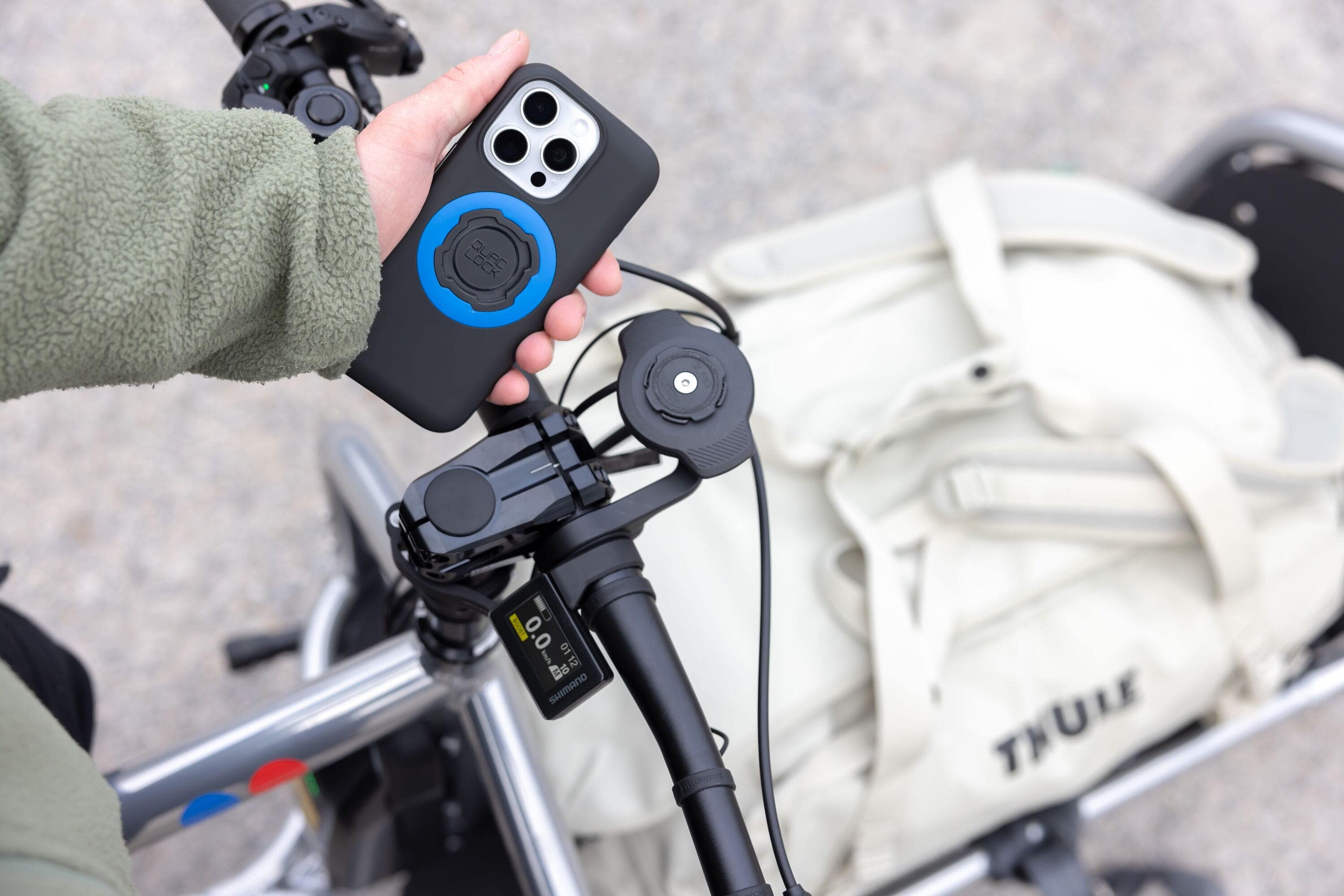 Quad Lock waterproof wireless charging head accessory for bike phone mounts, shown attached to a mobile device.