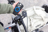 Quad Lock waterproof wireless charging head accessory for bike phone mounts, shown attached to a mobile device.