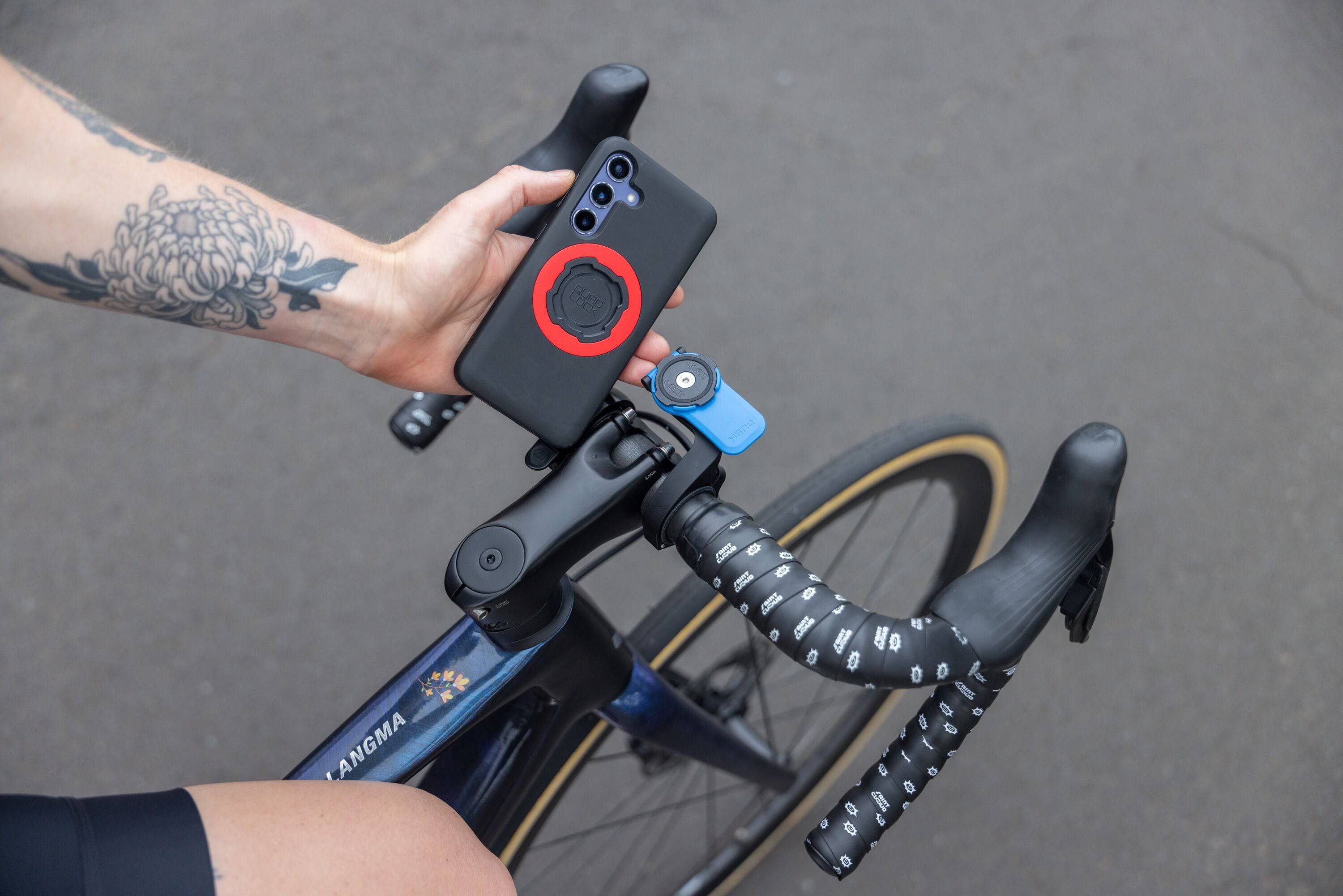 Quad Lock Out Front Mount V3 for smartphones with modular accessory compatibility, shown mounted on a bike handlebar.