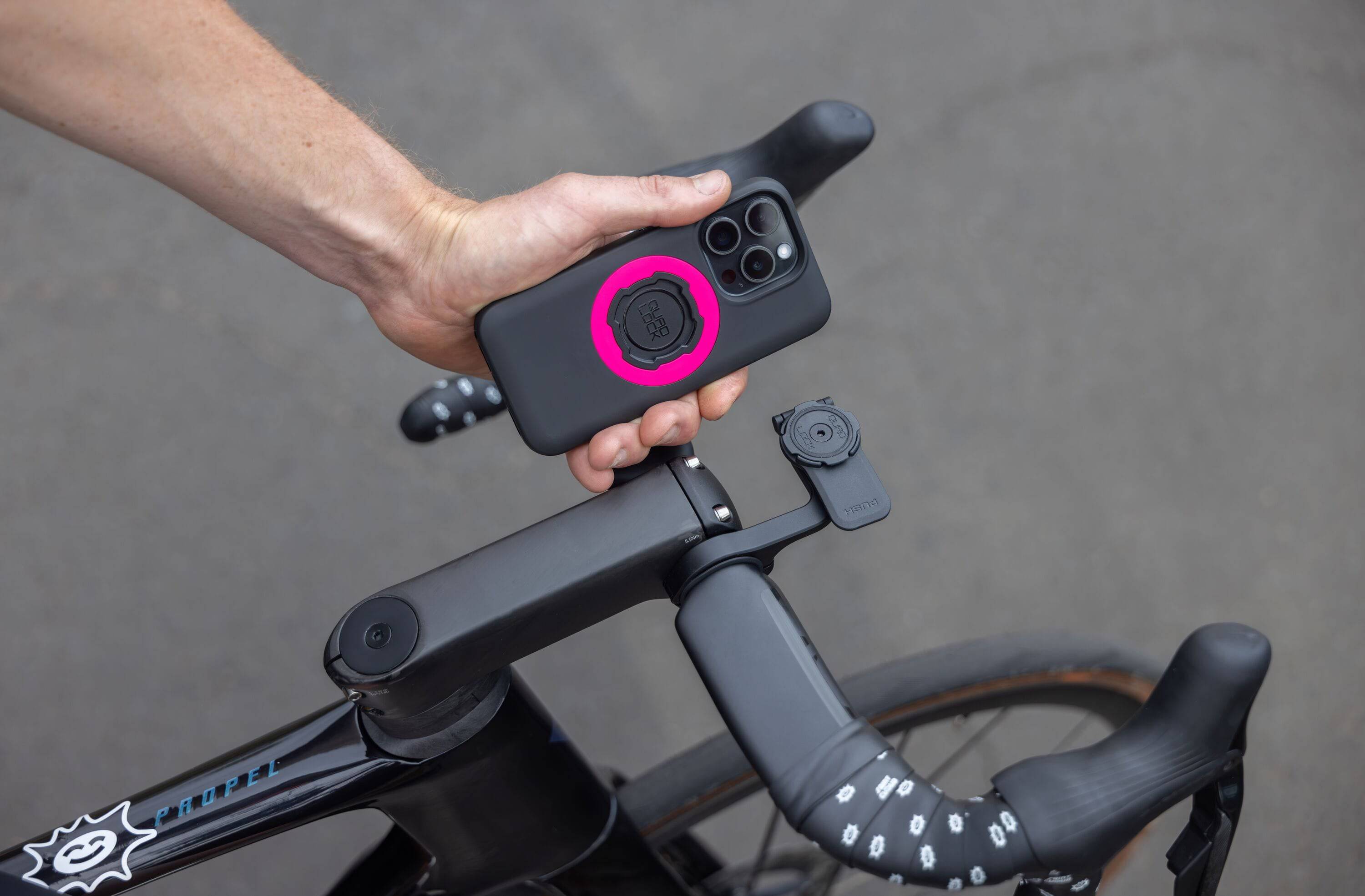 Quad Lock Out Front Mount Pro V2 bike phone mount attached to handlebars with a smartphone secured for easy access and 360° rotation.