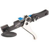 Park Tool HBT-1 hydraulic barb tool for brake hose cutting and installation, shown in a workshop setting with tools and work surface.