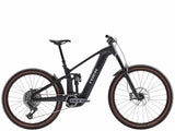 Trek Rail+ 9.8 GX AXS 2025 electric mountain bike with 29-inch wheels and Gen 5 motor, shown on rugged trail.
