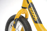 Yellow Ridgeback Scoot 2027 kids balance bike for toddlers age 2+ with a close-up of the bike's frame and handlebar details.