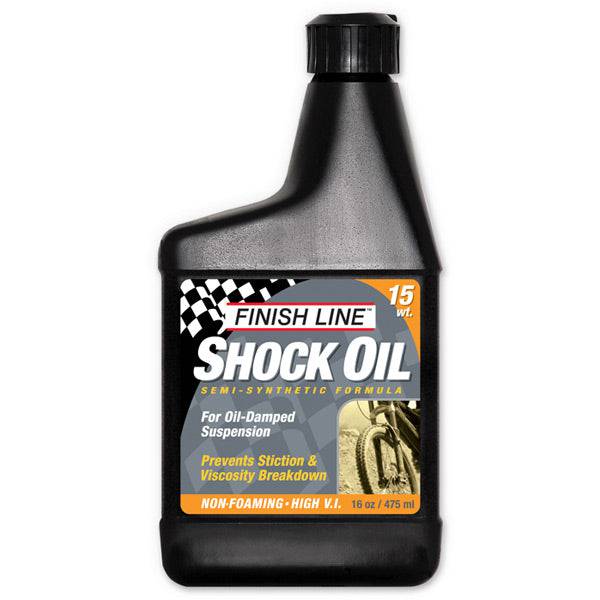 Finish Line Shock Oil 15 wt for bicycle suspension forks, 16 oz, shown in a workshop setting with oil container and tools.