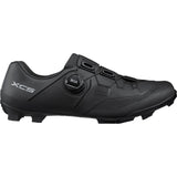 Shimano XC5 mountain bike shoes with BOA Fit System and carbon fiber midsole, showing the sleek black design and secure closure.