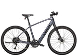 Trek Dual Sport+ 2 e-hybrid bike with HyDrive pedal assist and versatile accessories, shown with sleek frame and bike components.