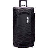 Black Thule Chasm rolling duffel bag showing durable weather-resistant fabric and sturdy wheels for travel accessories.
