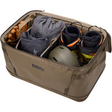 Thule Chasm Gear Hauler waterproof semi-rigid storage bag for travel and camping, shown in a natural outdoor setting.