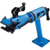 Park Tool PCS-12.2 bike repair stand with micro-adjust clamp mounted on workshop bench, suitable for home mechanic bike repairs