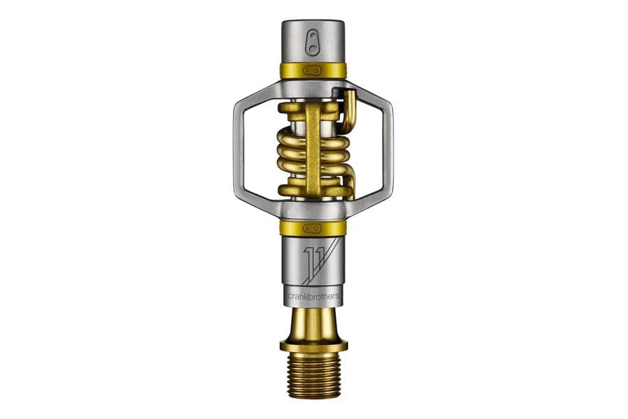 Crankbrothers Eggbeater 11 gold XC racing pedals with brass cleats and mud shedding design, close-up view of the lightweight components.