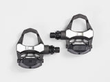 Bontrager Elite Road Pedal Set in black with cleats and adjustable tension on a bike pedal platform.