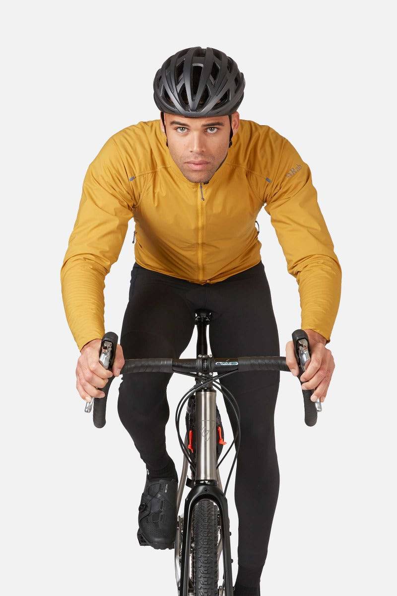 Rab VR Cinder Softshell Cycling Jacket in Sahara color, featuring Vapour-Rise™ technology for wind protection, worn by a cyclist.