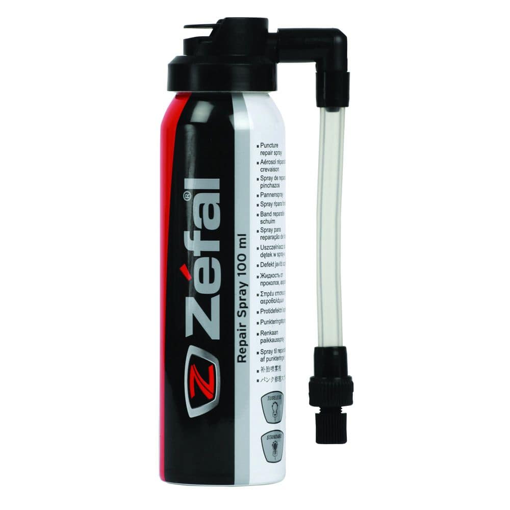 Zefal puncture repair spray for bikes, showing a workshop setting with the spray bottle and bike tire repair tools.