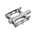 MKS Sylvan Track Next silver cycling pedal with one-sided design for track and road biking, mounted on a bike crank.