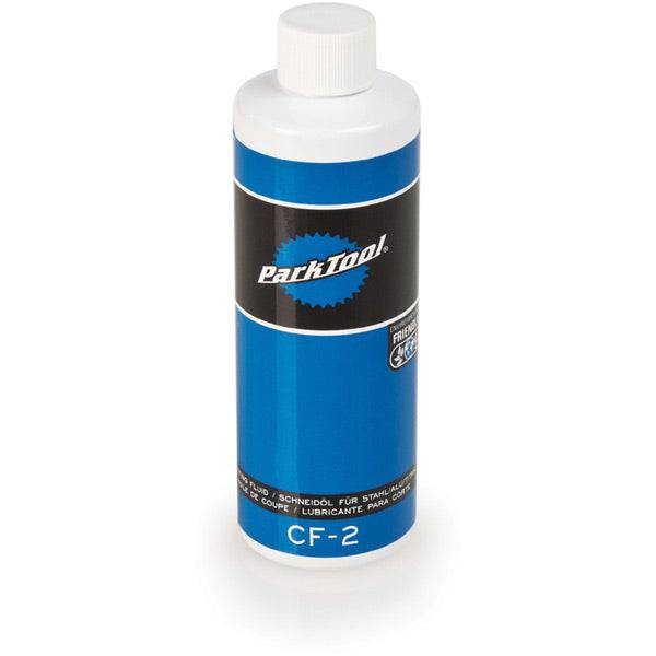 Park Tool CF-2 cutting fluid for metalworking, red liquid in a workshop setting, reduces friction and extends tool life.
