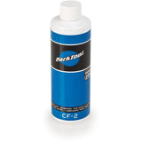 Park Tool CF-2 cutting fluid for metalworking, red liquid in a workshop setting, reduces friction and extends tool life.