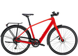 Trek FX+ 2 e-hybrid bike with hybrid frame, front lights, mudguards, rear rack, and pedal assist system in a city setting