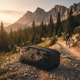 Black duffel bag on a mountain path with a cyclist in the background