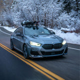 SeaSucker Classic Ski Rack vacuum mount attached to car holding four pairs of skis and snowboards, outdoor winter scene.