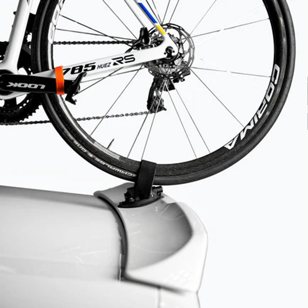 SeaSucker Compact Rear Wheel Strap securing a bike's rear wheel to a car for roof-mounted bike rack transportation.
