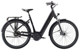Trek District+ 4 Guard lowstep electric hybrid bike for urban commuting, with sleek frame and integrated battery in a city setting.
