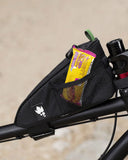 Miss Grape Node Adventure strap-mount top tube bag for cycling storage, shown attached to a bike frame in a scenic outdoor setting.