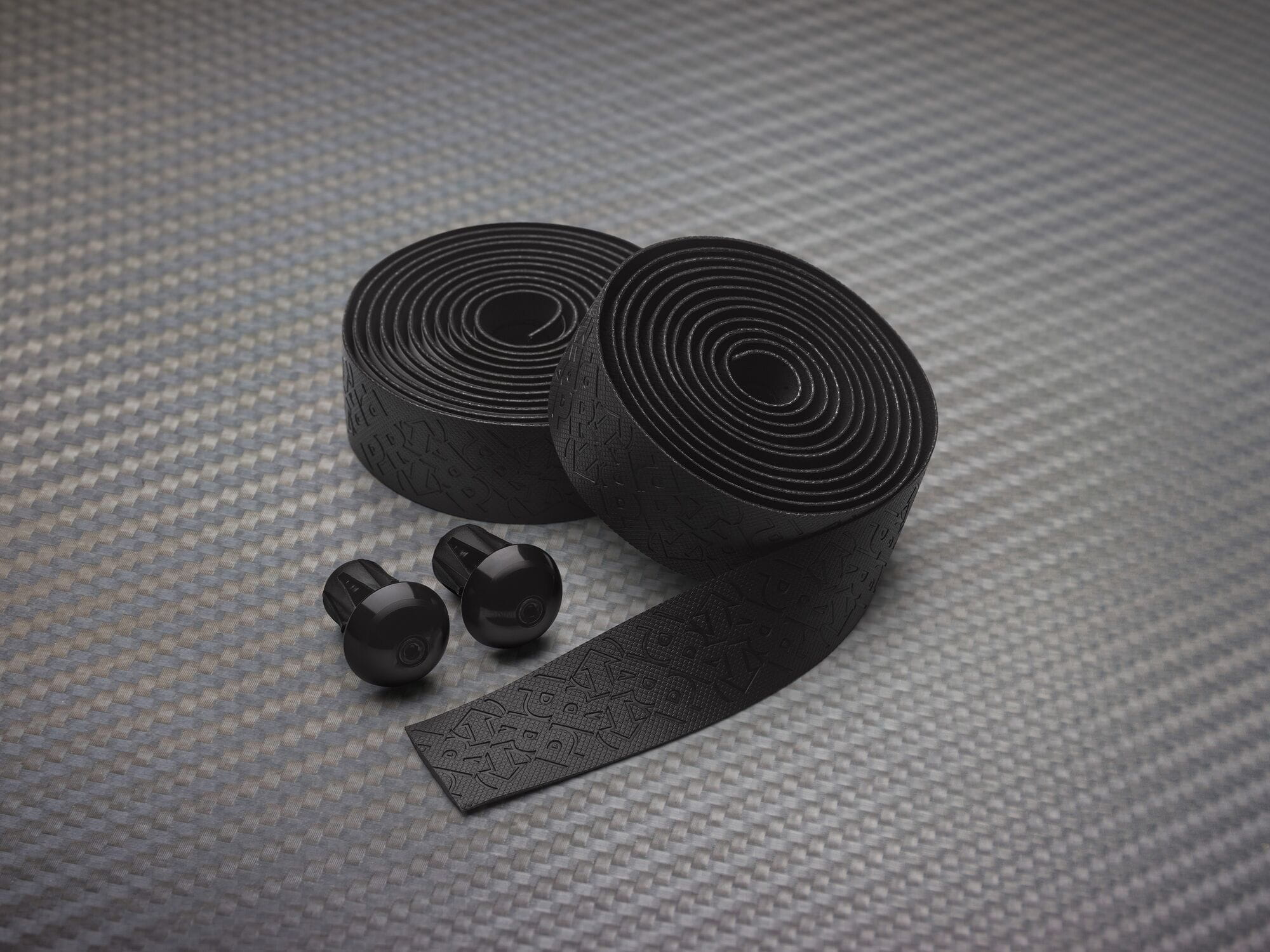PRO Pursuit Team handlebar tape with gel backing and alloy end caps for cycling, showing the textured black tape on handlebars.